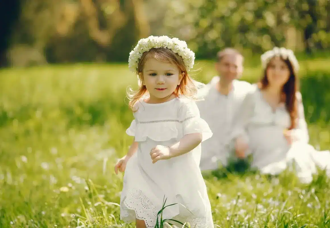 Jeune enfant qui vient d'être baptisée qui court dans l'herbe