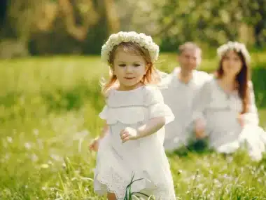 Jeune enfant qui vient d'être baptisée qui court dans l'herbe
